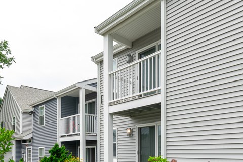 a white house with a porch and a balcony at Blue Hills Village, Canton, Massachusetts
