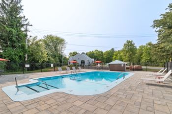 a swimming pool with lounge chairs and umbrellas in front of a house at Mansfield Meadows in Mansfield, MA
