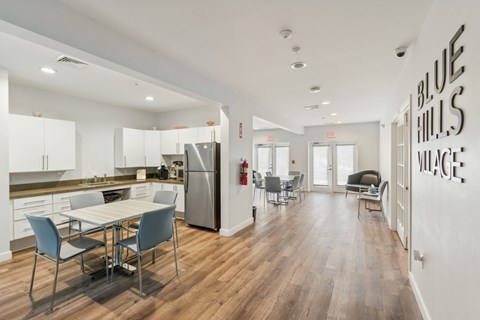 a dining room with a table and chairs and a kitchen with a stainless steel refrigerator at Blue Hills Village, Massachusetts, 02021