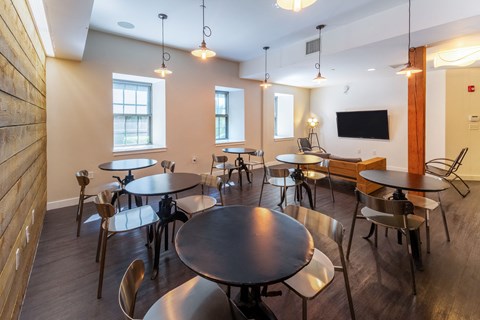 a dining room with tables and chairs and a tvat Ames Shovel Works Apartments, Massachusetts, 02356