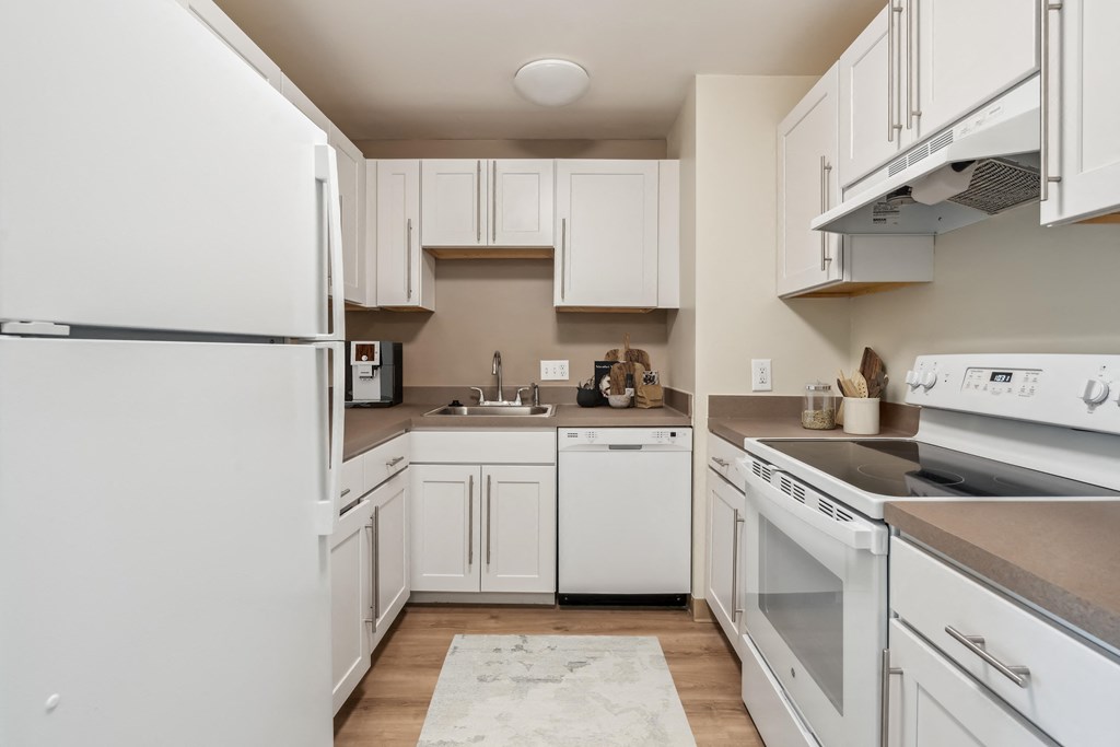 a kitchen with white cabinets and appliances and a sink at Chapman House, E. Boston, MA