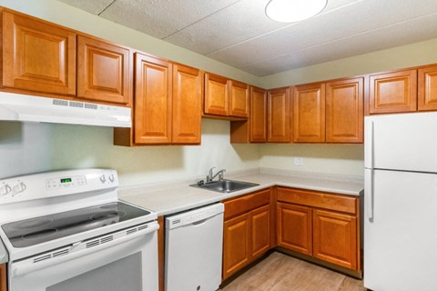A kitchen with white appliances and wooden cabinets.