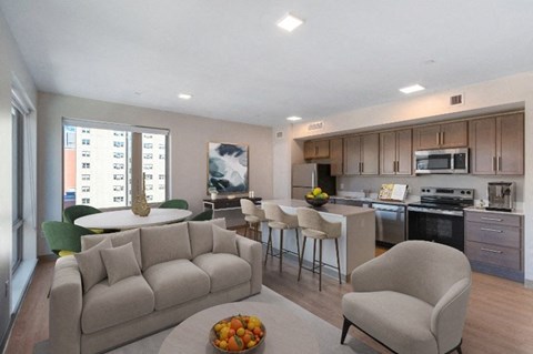 A modern living room with a grey sofa and a dining table with chairs.