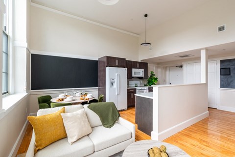 A modern living room with a white couch and a dining table with chairs.