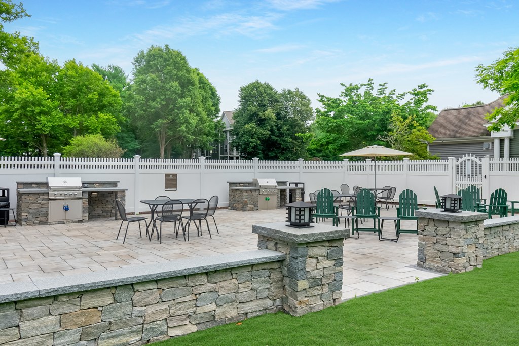 a patio with tables and chairs and a fence at Woodlands at Abington Station, Abington