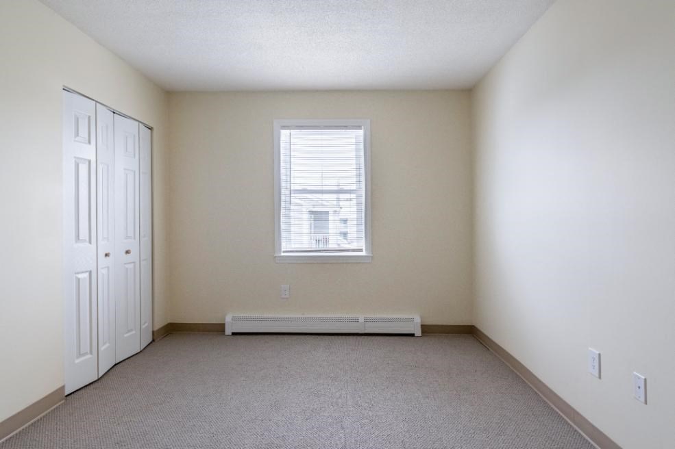 a bedroom with a closet and an open door at at North Stoughton Village Apartments in Stoughton, MA
