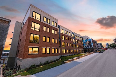A modern building with a long row of windows is illuminated by the setting sun.