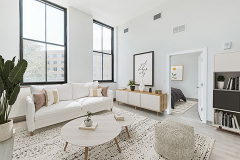 A living room with a white couch, a coffee table, and a large window.