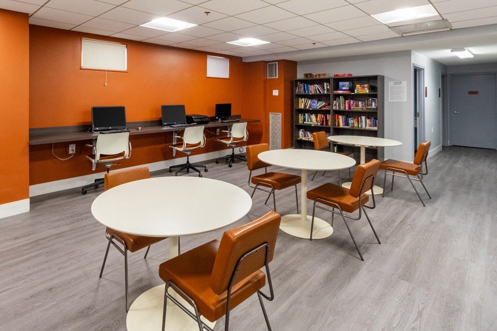 a common room with tables and chairs and a library at Mill House Apartments, Greenfield, MA 01301