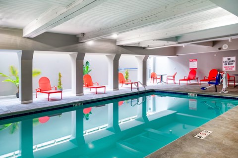 a swimming pool in a building with red chairs at Royal Worcester Apartments, Massachusetts, 01610