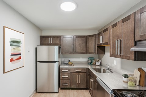 A kitchen with brown cabinets and a stainless steel refrigerator.at Rolling Green Apartments, Massachusetts, 01002