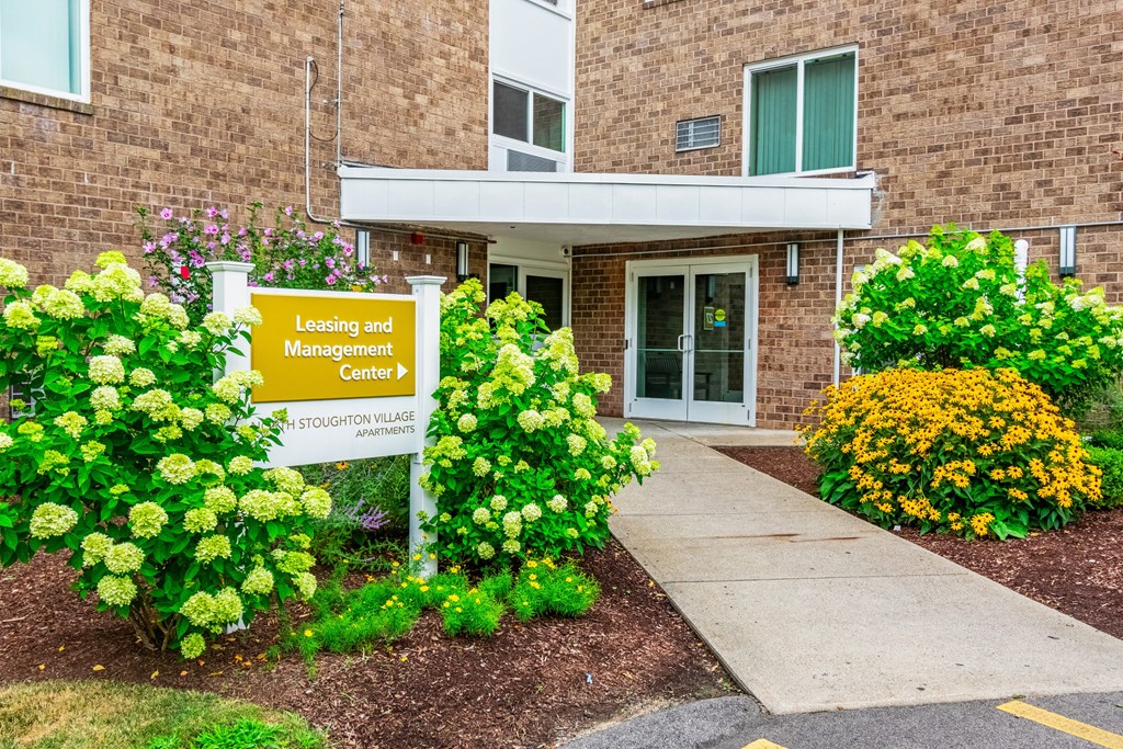 the front of a building with a loading and management center sign at North Stoughton Village, Massachusetts