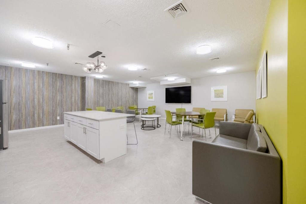 A Community Room with a table and chairs and a kitchen at North Stoughton Village Apartments in Stoughton, MA