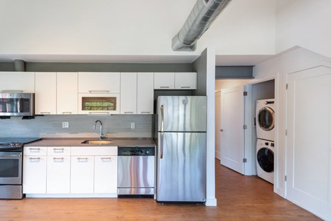 a kitchen with white cabinets and stainless steel refrigerator