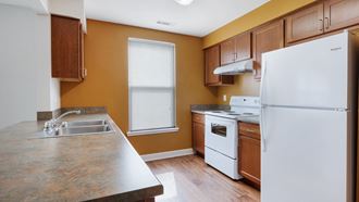 a kitchen with white appliances and wooden cabinets at Waterfront Apartments, Buffalo, NY