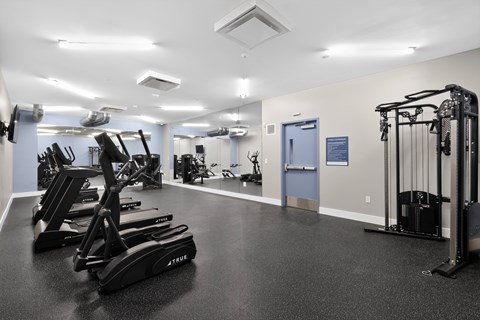 A gym with a variety of equipment including treadmills, weights, and exercise machines.