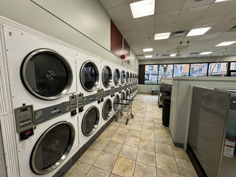 A row of front-loading washing machines in a public laundromat at Tai Tung Village, Boston, MA 02111