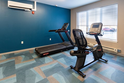 A gym with a treadmill and a stationary bike. at 35 Broadway Apartments, Menands, New York