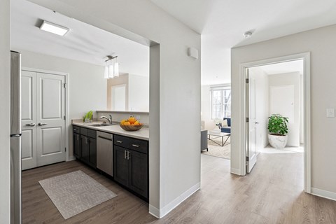 A kitchen with a refrigerator, sink, and a counter with fruit on it.