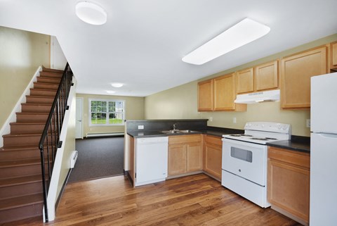 A kitchen with wooden cabinets and a staircase.