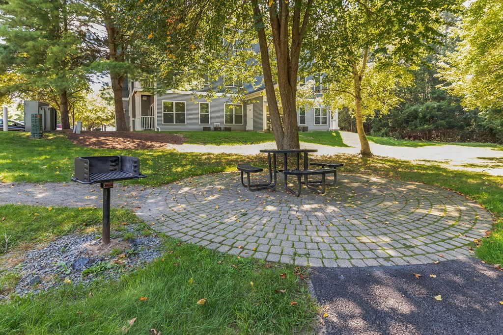 a picnic area with a table and a grill in front of a house at Woodlands at Abington Station, Abington, MA, 02351