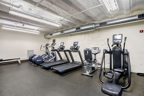 A gym with treadmills, elliptical machines, and other exercise equipment at Brewery Square Apartments, New Haven , CT