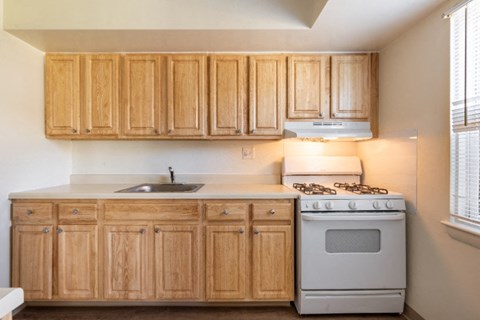 A kitchen with wooden cabinets and a white stove.