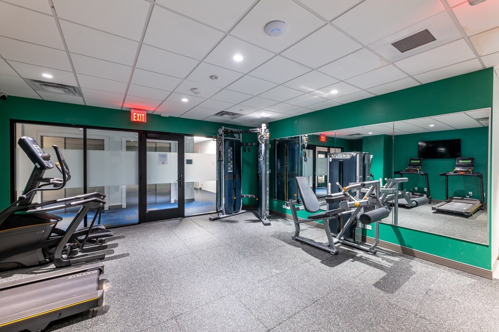 a gym with exercise equipment and mirrors in a building with green walls  at 140 Clarendon, Massachusetts, 02116