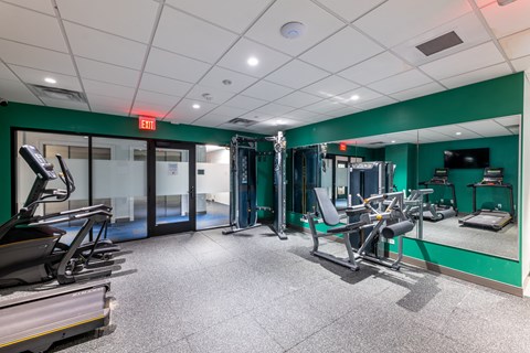 a gym with exercise equipment and mirrors in a building with green walls  at 140 Clarendon, Massachusetts, 02116