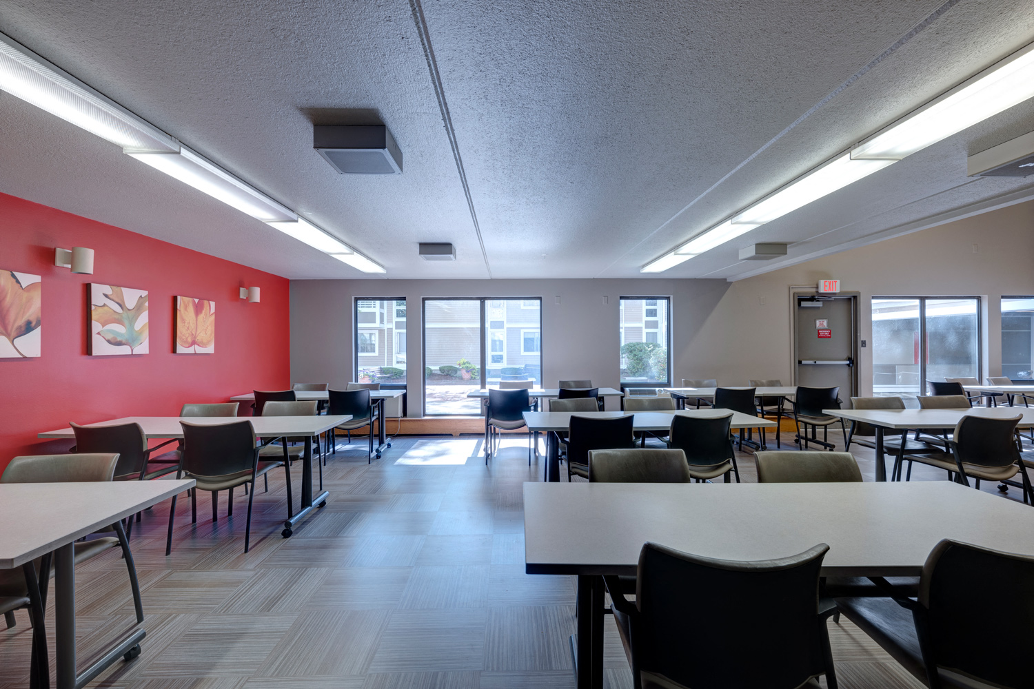 a dining room with tables and chairs and a red accent wall