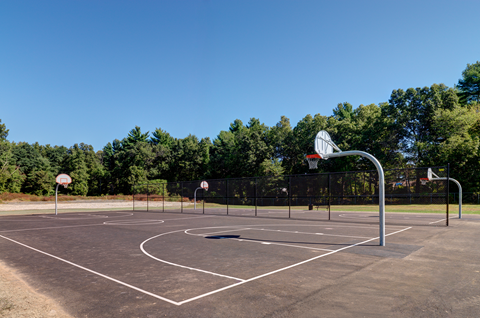A basketball court with a hoop and a sign on the ground at Colonial Estates Apartments, Massachusetts, 01119