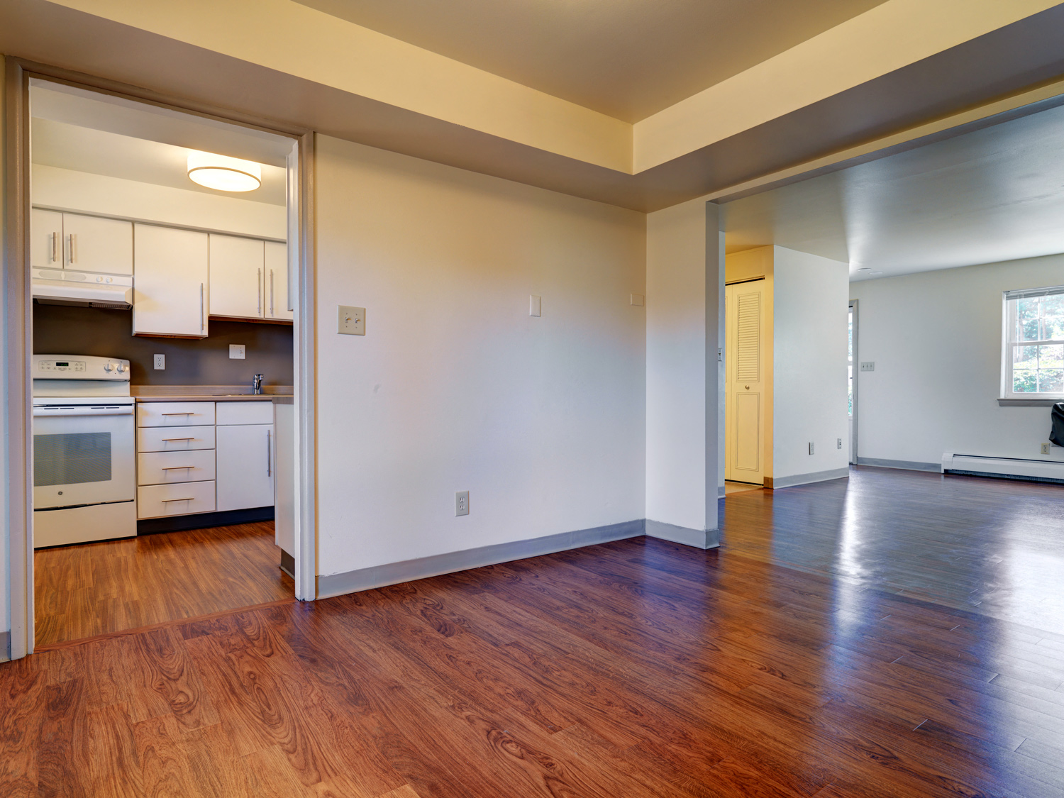 A kitchen with white cabinets and a wooden floor.