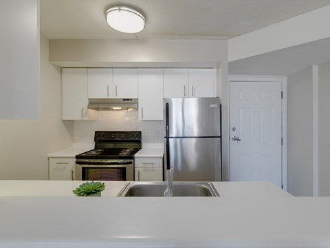 a kitchen with white counters and a stainless steel refrigerator