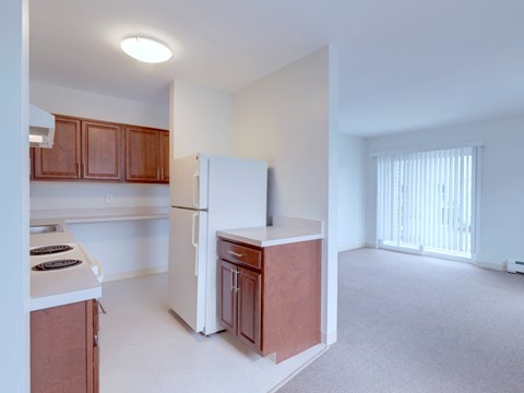 an empty kitchen with a white refrigerator and a counter top