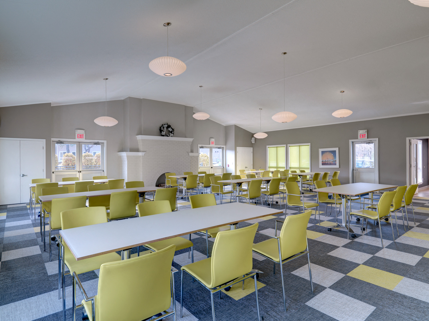 a dining room with long tables and yellow chairs