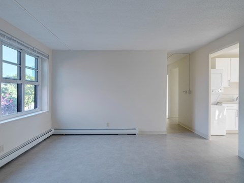 an empty living room with white walls and a window
