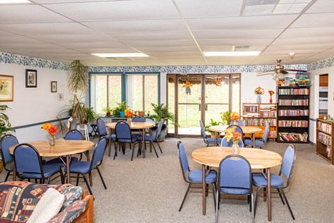 A room with tables and chairs and a bookcase.