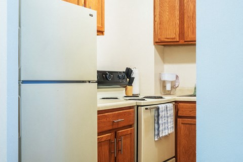 A white refrigerator is in a kitchen with wooden cabinets.