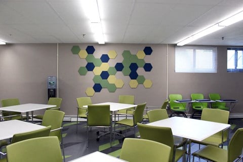 a dining room with tables and chairs and a wall with a cluster of squares on