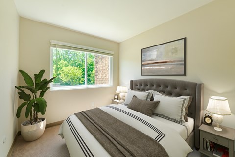 A bedroom with a large bed and a potted plant.
