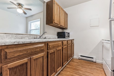A kitchen with wooden cabinets and a marble countertop.