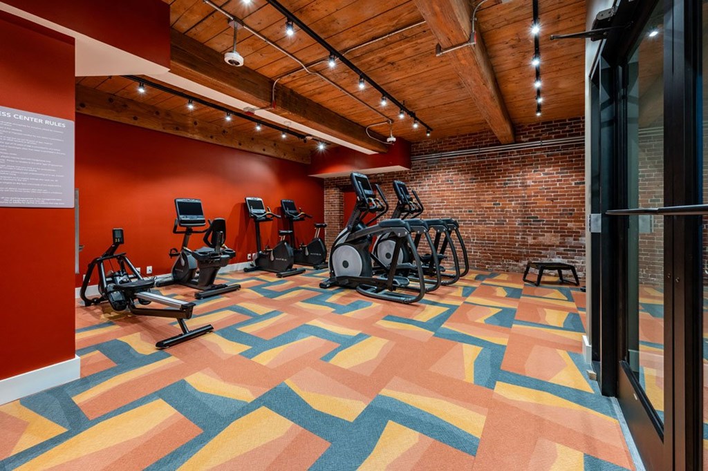 A gym with a variety of exercise equipment and a colorful floor A gym with a variety of exercise equipment and a colorful floor at The Cordovan at Haverhill Station, Haverhill, MA