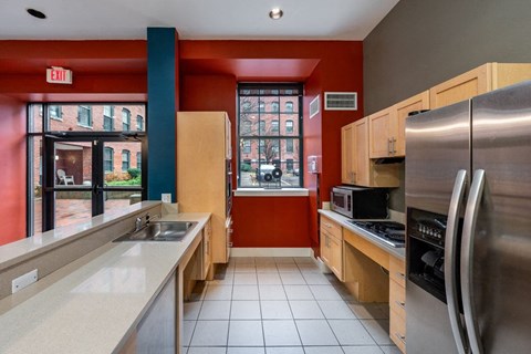 A kitchen with a red wall and a stainless steel refrigerator at The Cordovan at Haverhill Station, Haverhill, MA