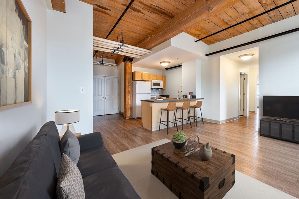 A living room with a grey couch and a wooden coffee table at The Cordovan at Haverhill Station, Haverhill, MA