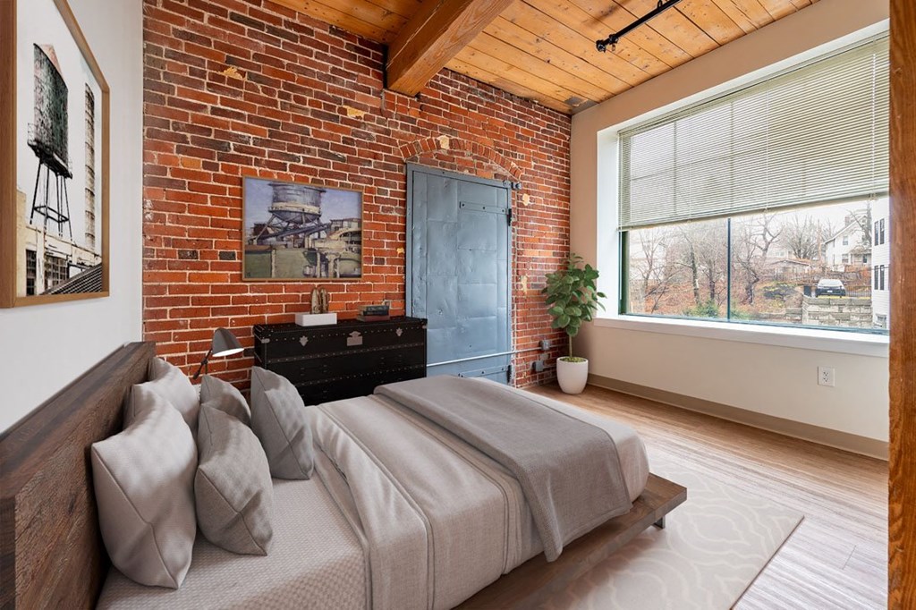 A bedroom with a bed, a dresser, and a window at The Cordovan at Haverhill Station, Haverhill, MA