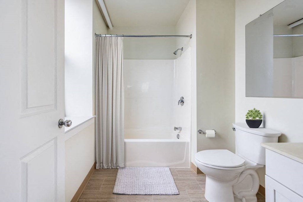 A white bathroom with a toilet, sink, and bathtub at The Cordovan at Haverhill Station, Haverhill, MA