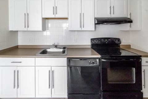 a kitchen with white cabinets and black appliances