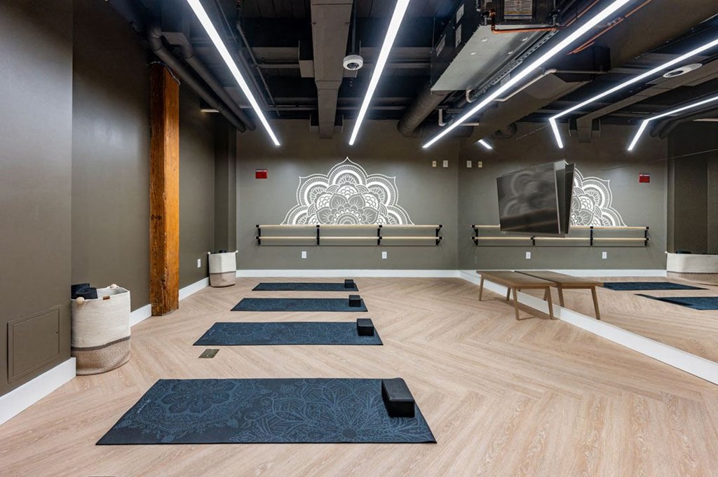 A yoga studio with wooden floors and mats at The Cordovan at Haverhill Station, Haverhill, MA
