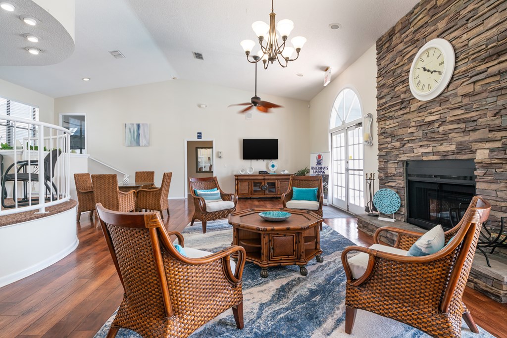A living room with a fireplace and a large clock on the wall Fishermans Landing Apartments in Ormond Beach, FL.