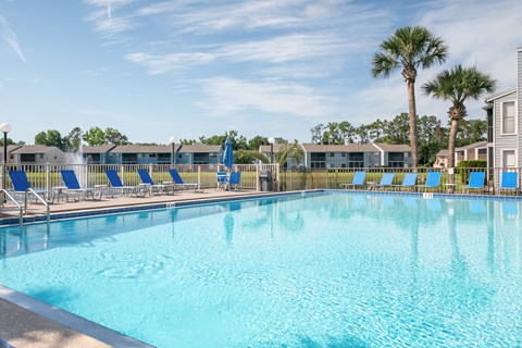 A large swimming pool with blue water and lounge chairs Fishermans Landing Apartments in Ormond Beach, FL.